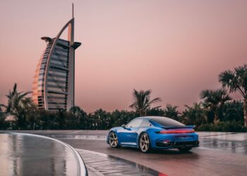 A static Porsche 911 in blue with the Burj Al Arab in the background