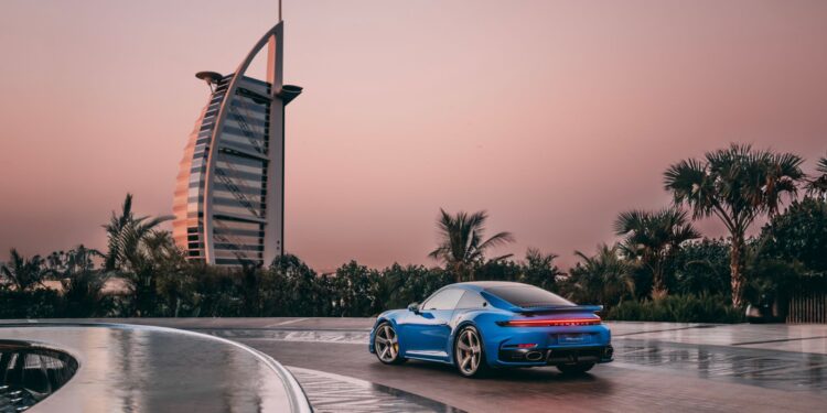 A static Porsche 911 in blue with the Burj Al Arab in the background