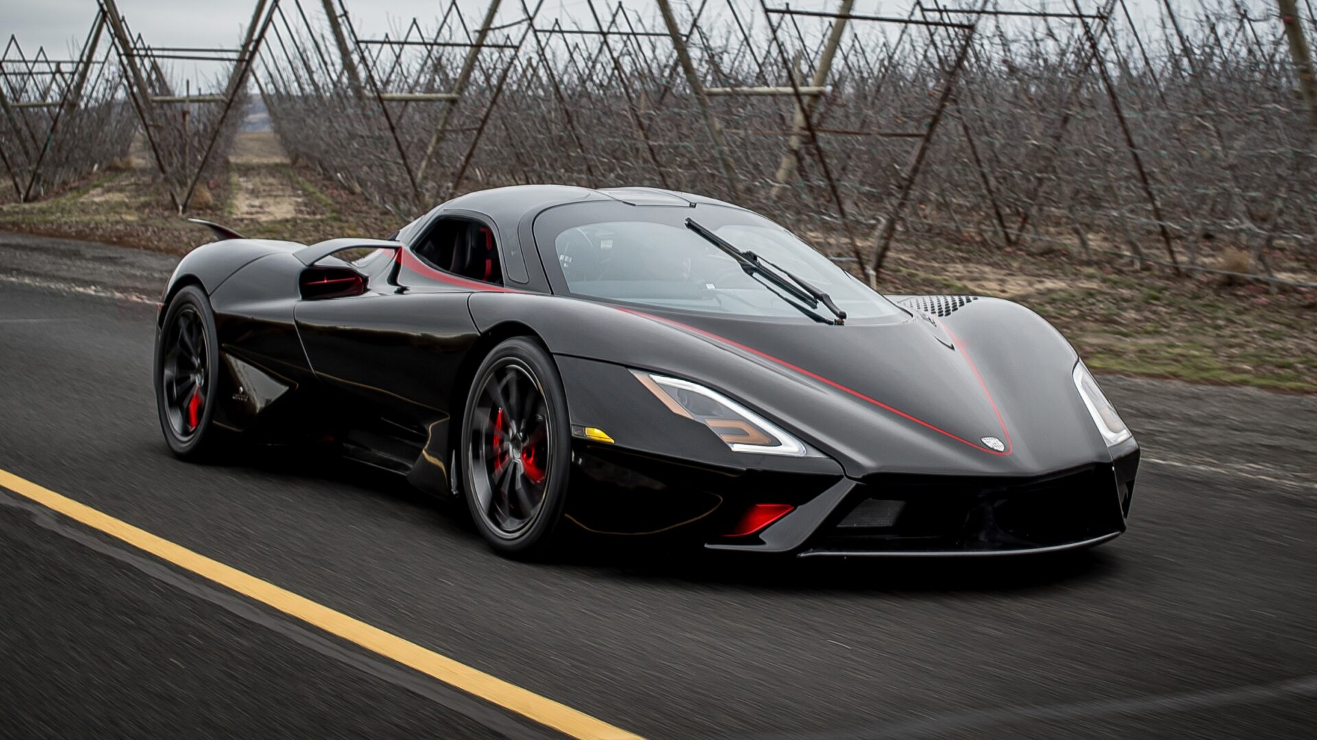 Dynamic shot covering the front three-quarters of a black SSC Tuatara with red accents