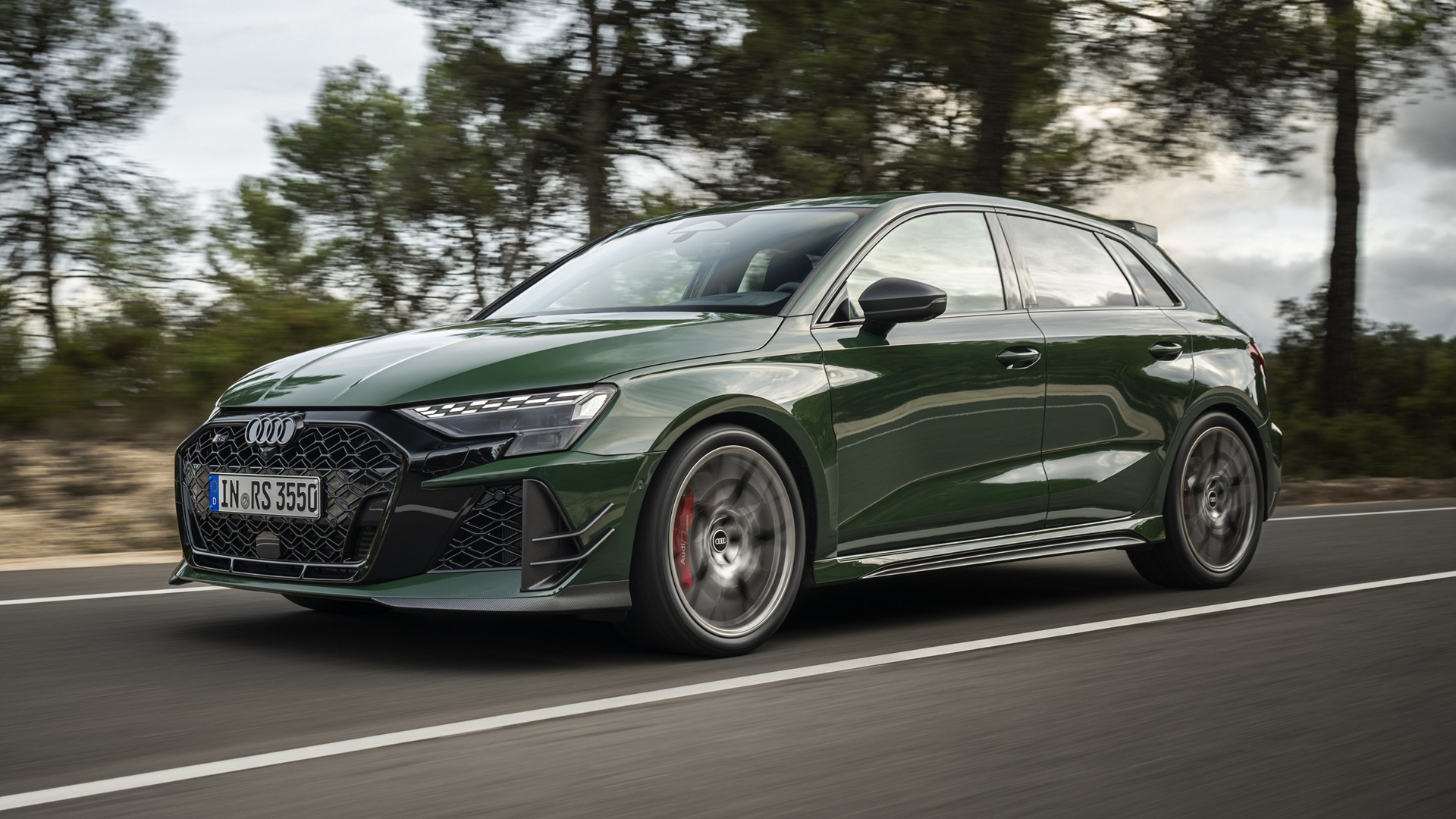 A dynamic shot, covering the front three-quarters, of a Malachite green Audi RS 3 Sportback competition limited
