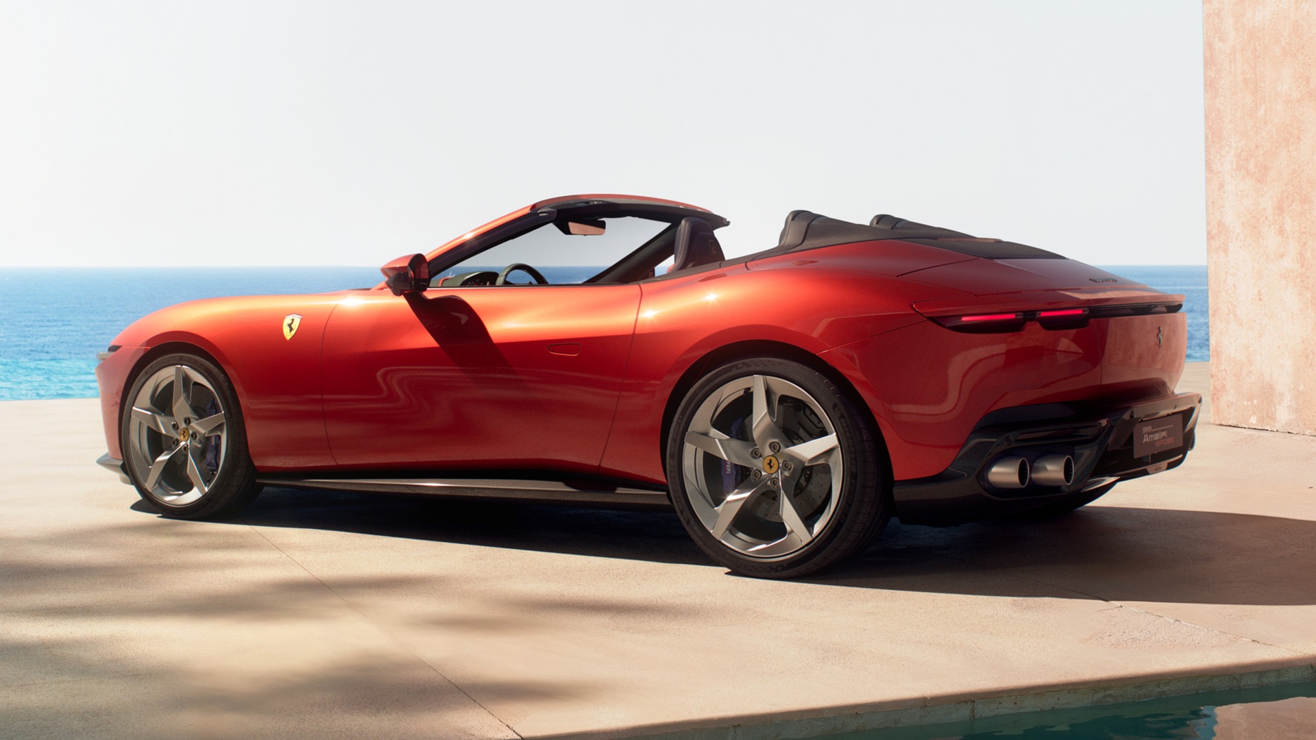 A static shot covering the rear three-quarters of the new Ferrari Amalfi Spider in its exclusive Rosso Tramonto paint.