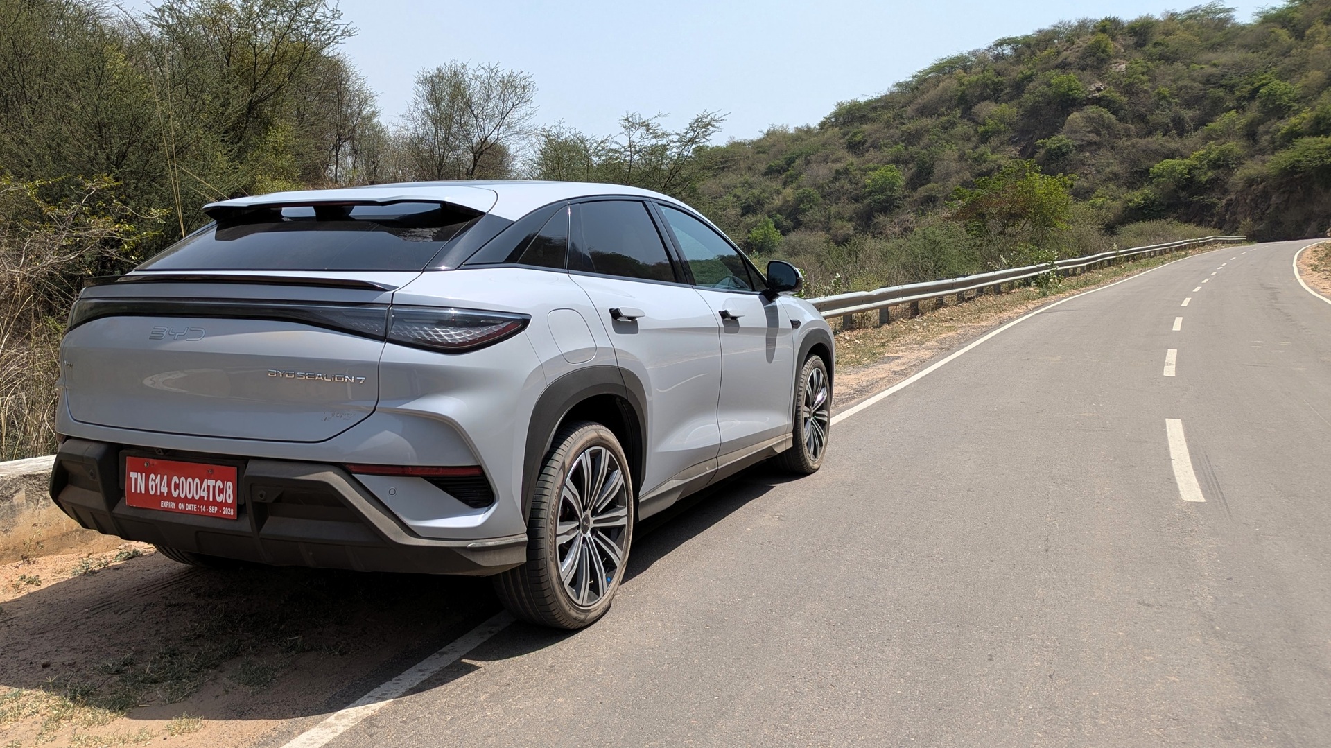 The three-quarters of a BYD Sealion 7 parked on the side of a twisty road in the Gurugram Aravallis