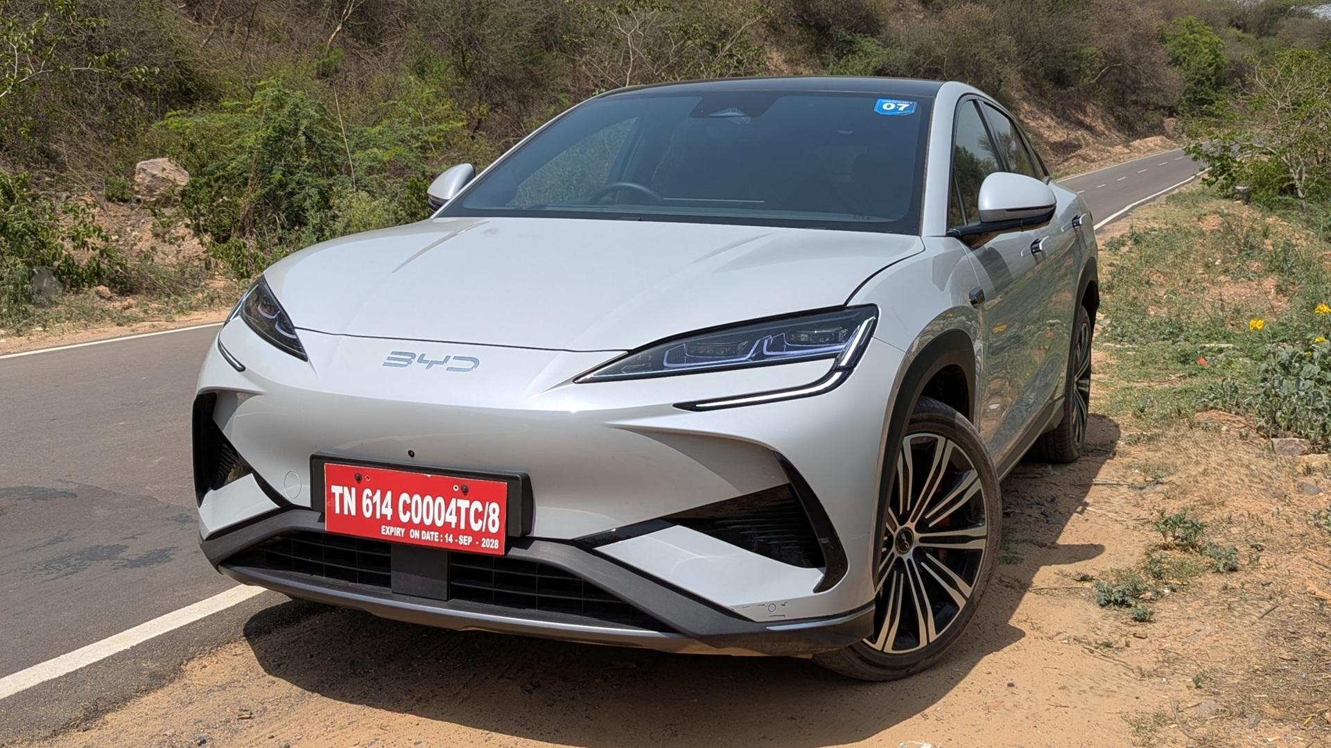 The front shot of a BYD Sealion 7 parked on the side of a twisty road in the Gurugram Aravallis