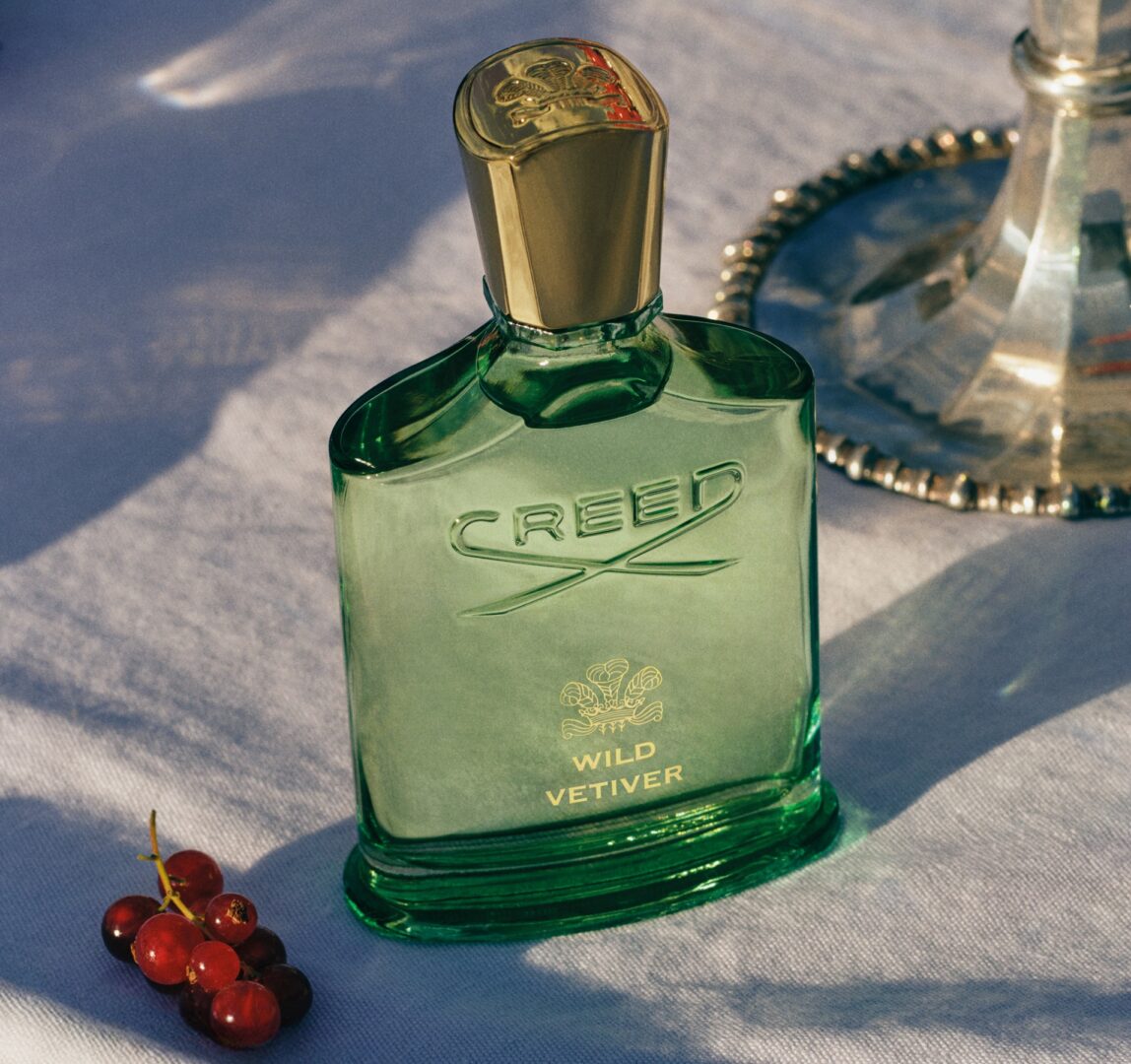 The green bottle of the Wild Vetiver by The House of Creed kept on a table alongside berries