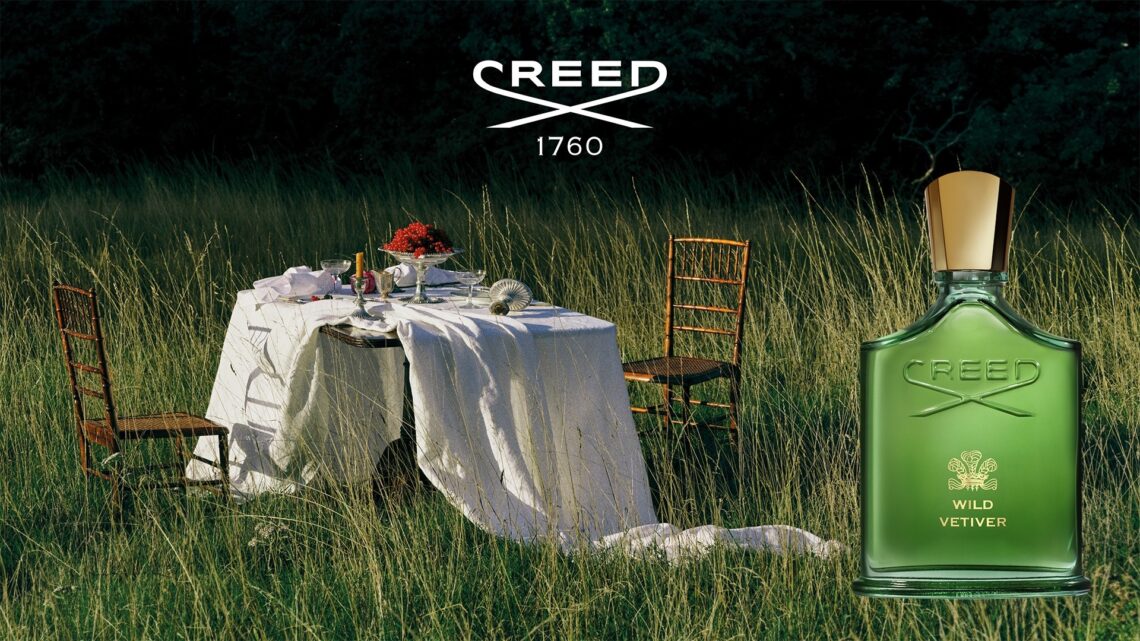 The green bottle of the Wild Vetiver by The House of Creed placed next two a dining table for two in the open