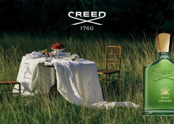 The green bottle of the Wild Vetiver by The House of Creed placed next two a dining table for two in the open