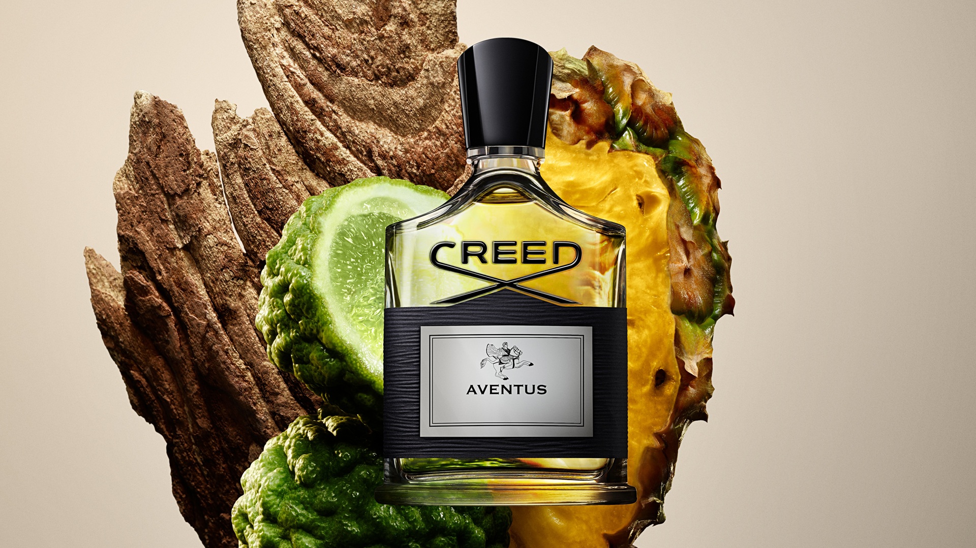 A Creed Aventus bottle with the elements of its frangrance notes behind.