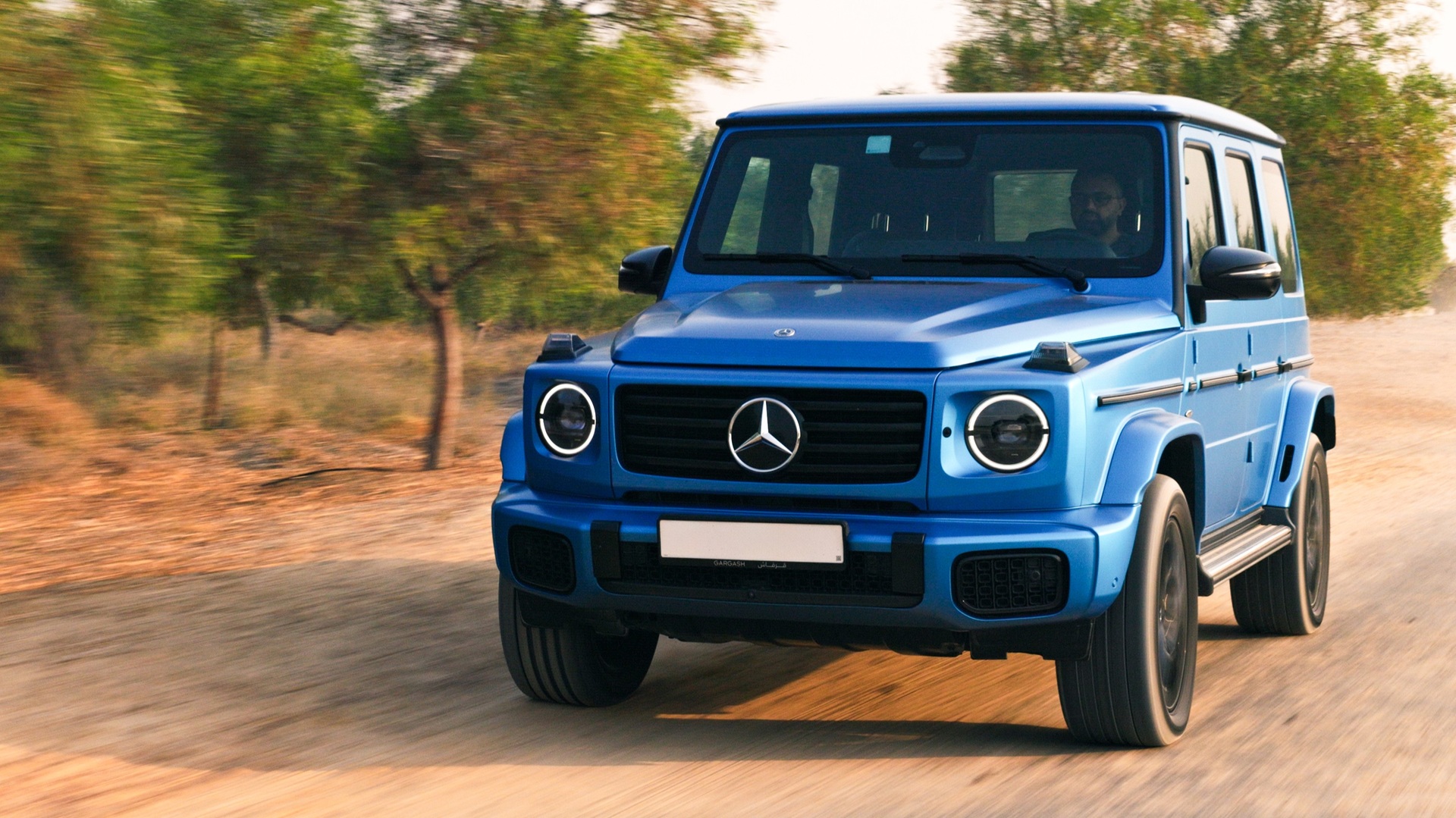 A dynamic shot of a blue Mercedes-Benz G 580, the Electric G-Wagen, taken from the front-right side