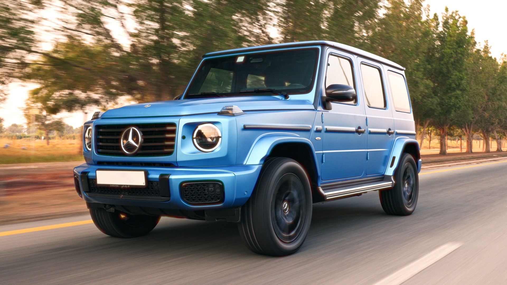 A dynamic shot of a blue Mercedes-Benz G 580, the Electric G-Wagen, taken from the front-right side