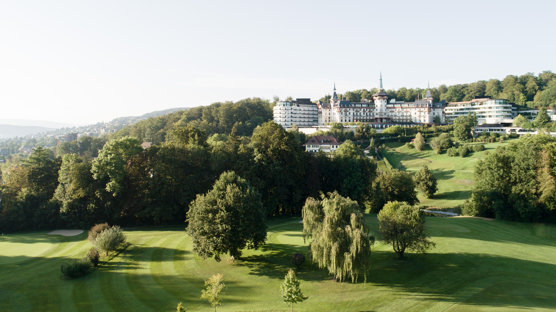 An extra-wide-view exterior shot of The Dolder Grand Zurich, covering the greenery around the property