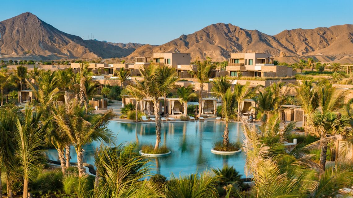 A wide shot of the Six Senses AMAALA, with the common swimming pool at the centre and mountains in the backdrop.