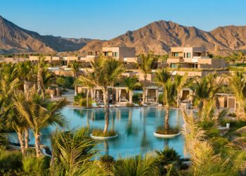 A wide shot of the Six Senses AMAALA, with the common swimming pool at the centre and mountains in the backdrop.